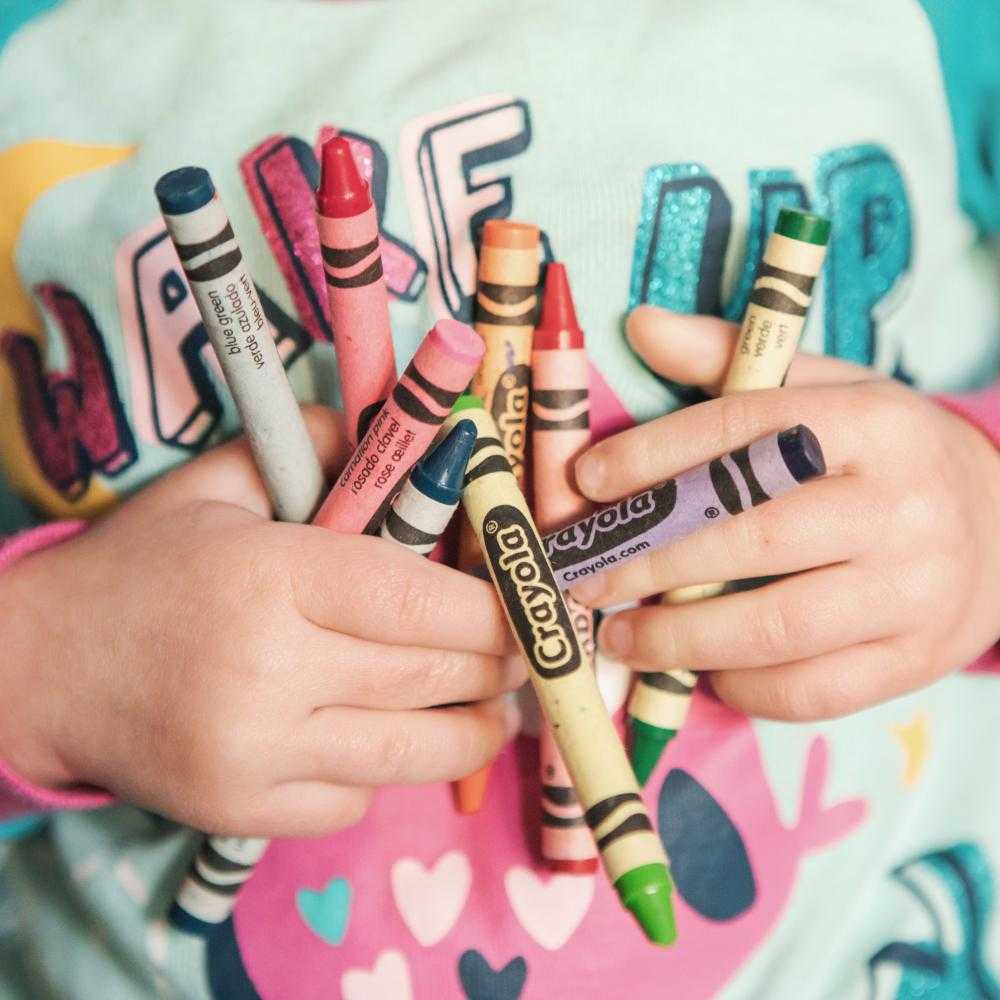 Child holding colorful crayons
