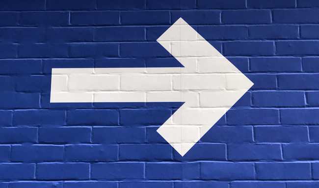 white arrow and blue background painted on bricks showing the onward, the way forward