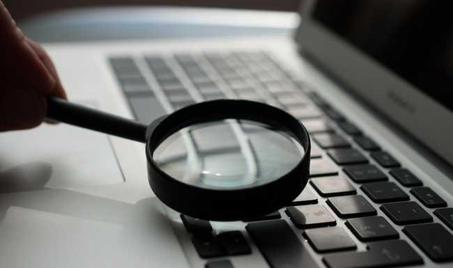 Magnifying glass hovering over a laptop keyboard