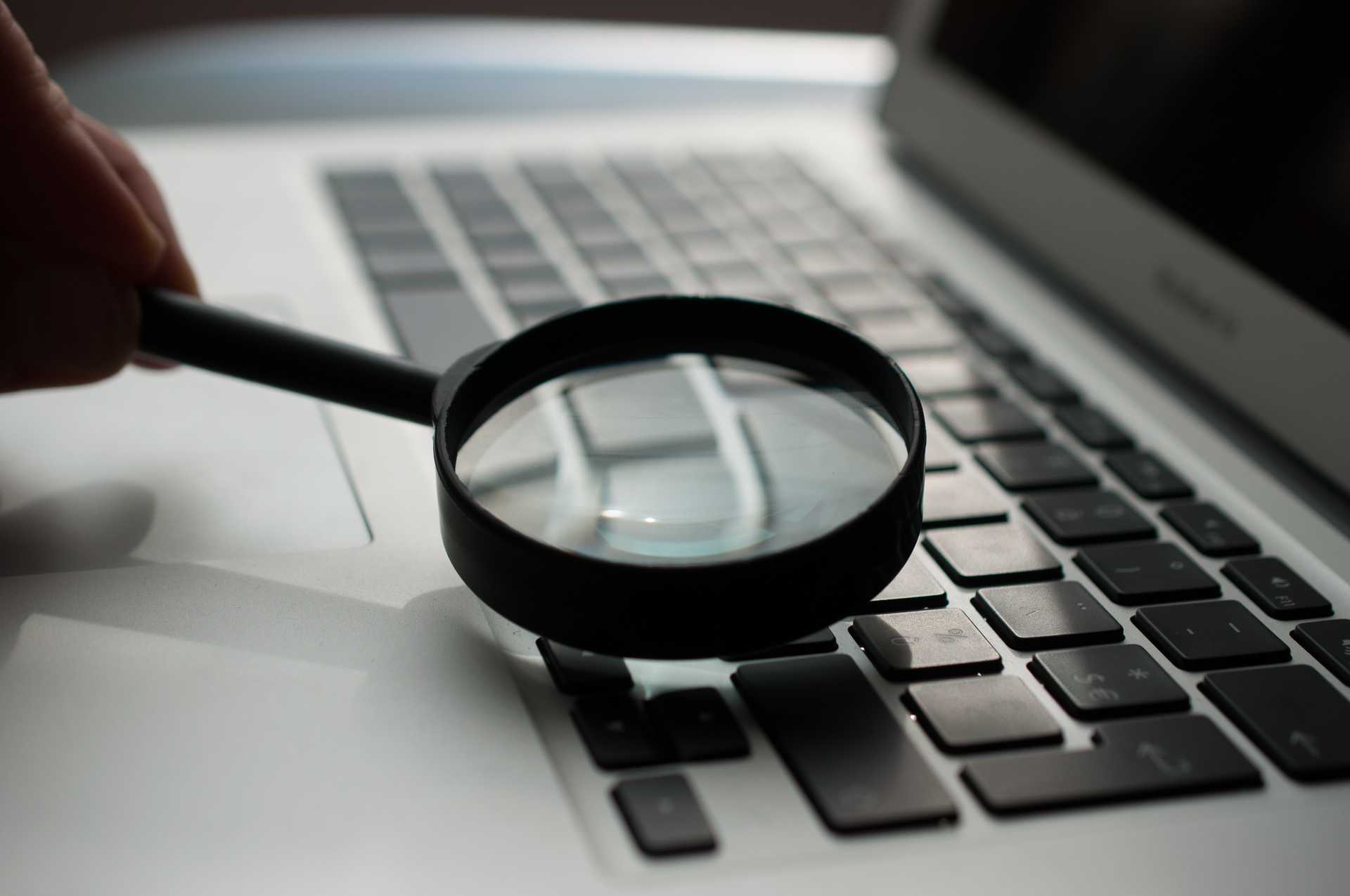 Magnifying glass hovering over a laptop keyboard